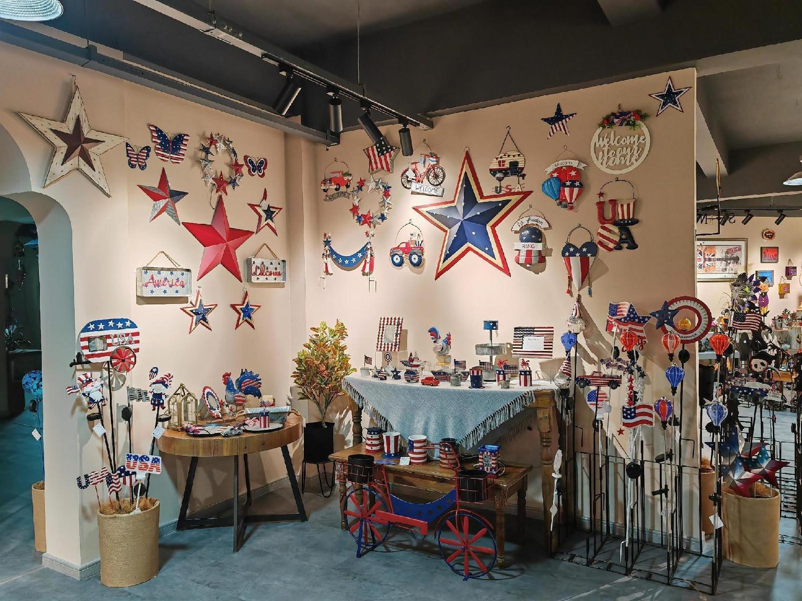 An Americana wall: barn stars, flag bunting and welcome signs above a draped table of small red-white-and-blue pieces