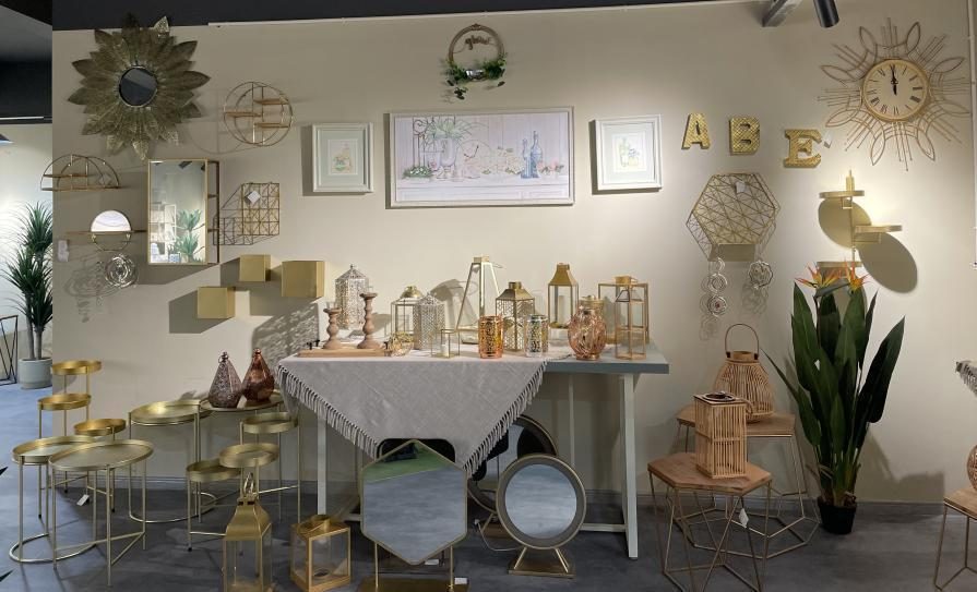 A styled corner of lanterns, vases and framed pieces on a linen-covered table