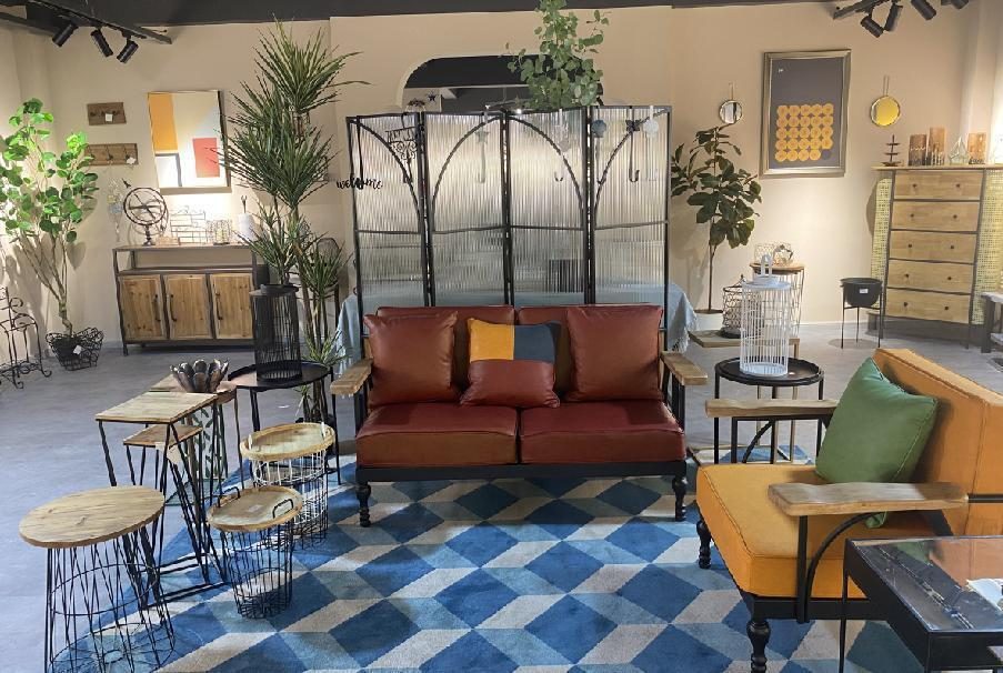 A living-room vignette with a rust sofa, stools and iron shelving units